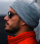 Homem usando óculos de sol masculino Sunset e gorro cinza, destacando estilo e proteção.